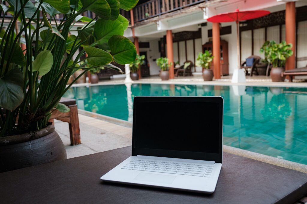 laptop of a remote digital nomad against the backdrop of a beautiful pool in the hotel